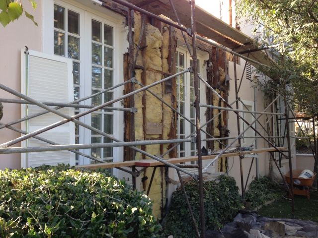 Construction scaffolding and exposed insulation on the side of a house