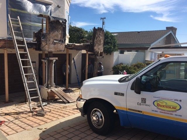 A DeckTech, Inc. truck in the driveway of a home and construction being performed on a deck