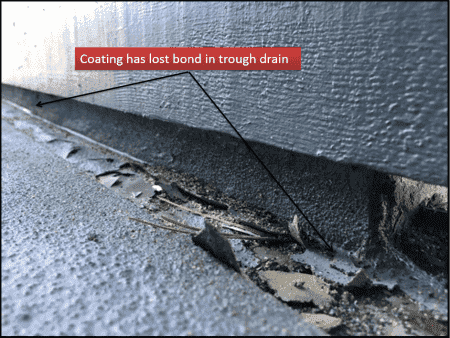 Peeling deck coating that has lost its bond in the trough drain