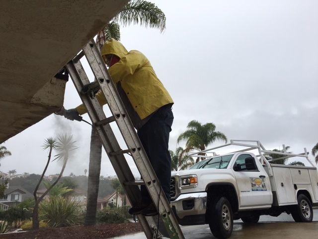 A San Luis Obispo deck contractor on a ladder beginning to open up the deck to perform repairs